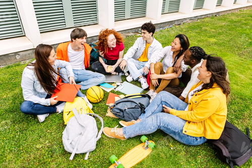 Preview: Happy student college friends relaxing together sitting on campus grass