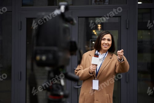Preview: Multiracial female journalist conducts an interview outdoors with a microphone in her hand
