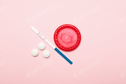 Preview: Condom, pills and pregnancy test on pink background