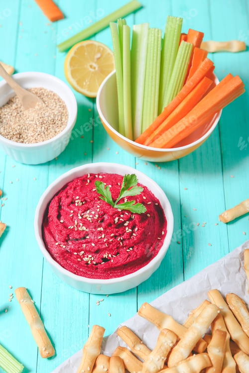 Preview: Bowl of beetroot hummus, sesame, carrot and celery crudites and breadsticks