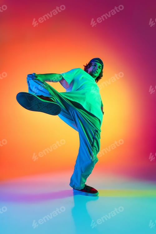 Preview: Conceptual portrait of young man, hip-hop dancer in stylish clothes in action isolated on colorful