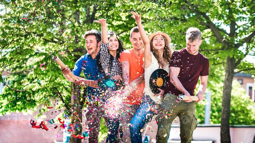 Preview: Happy amused friends having fun out side cheering with confetti