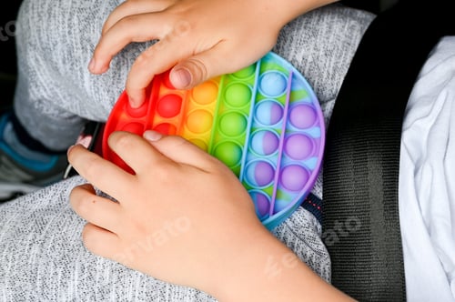 Preview: kids anti stress sensory pop it fidget push toys in kid's hands. child playing with a toy in a car