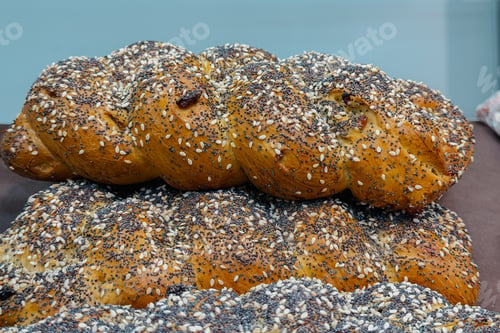 Preview: Delicious golden brown freshly baked braided bread loaves with poppy and sesame seeds at bakery