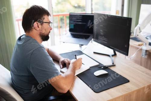 Preview: male programmer writing program code sitting at the workplace
