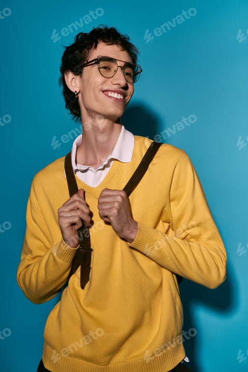 Preview: Charming young man shows off stylish outfit against vibrant blue backdrop