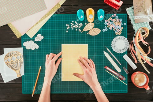 Preview: cropped image of designer sitting at working table with template for scrapbooking postcard