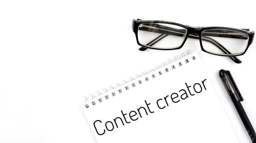 Preview: Reading glasses and notebook with word content creator on a white background