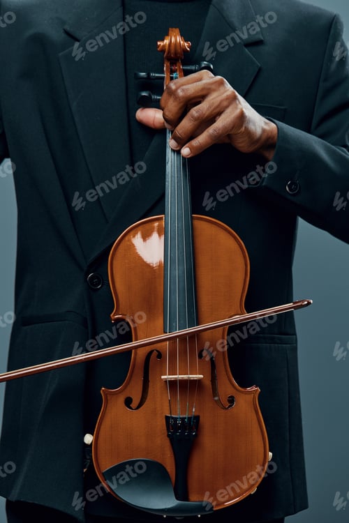 Preview: Closeup of elegant man in suit holding a violin in front of dark background