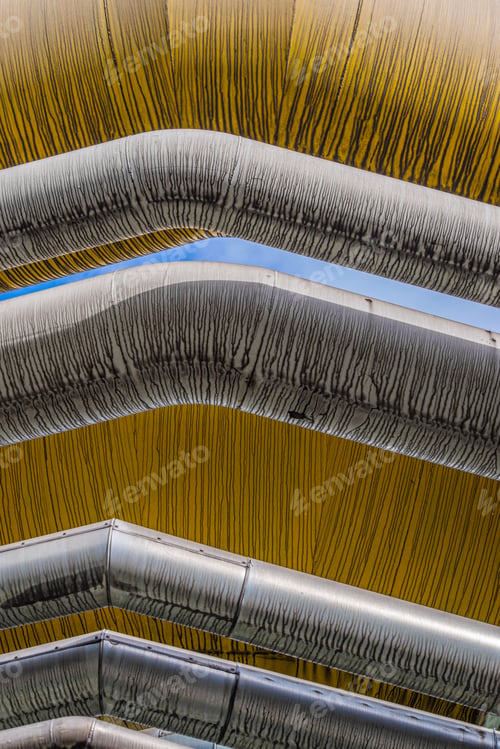 Preview: Low angle view of industrial plant pipelines under the blue sky