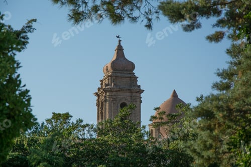 Preview: Church of San Giuliano behind trees with a blue sky in the background in Erice, Italy