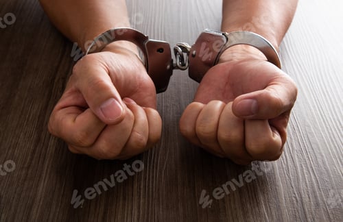 Preview: Arrested criminal hands locked in handcuffs.