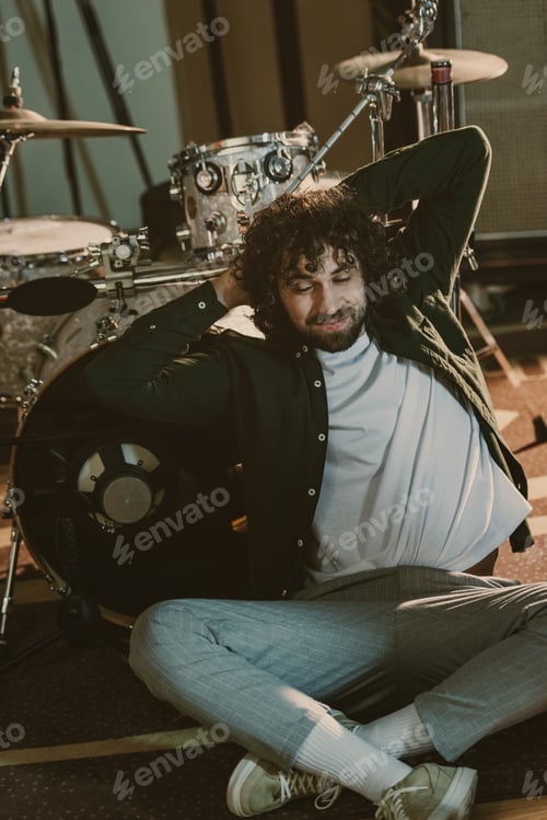Preview: happy bearded drummer relaxign while leaning back on drum set