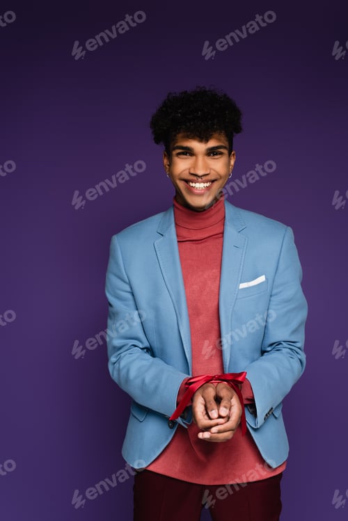 Preview: happy african american man tied with red ribbon on purple