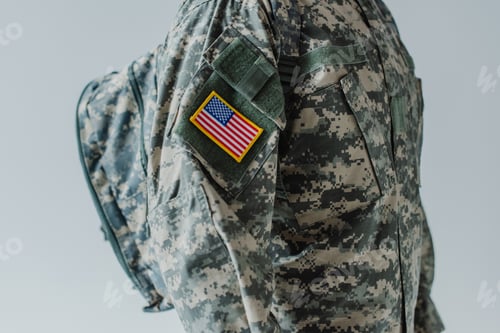Preview: cropped view of American serviceman in army uniform standing with backpack isolated on grey