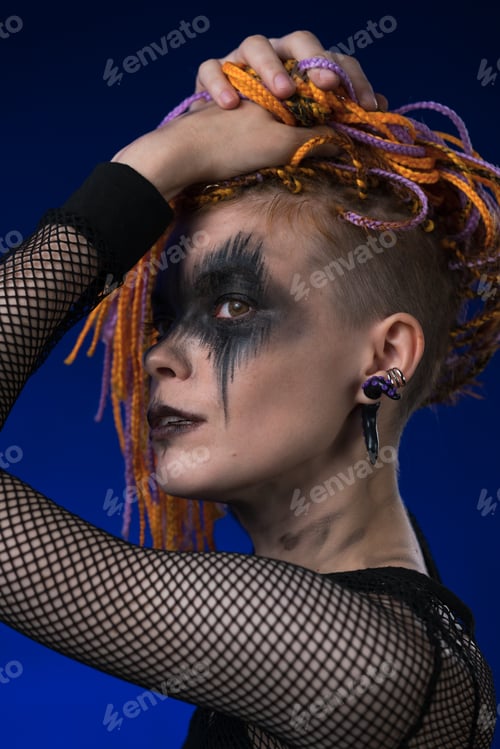 Preview: Headshot of young woman with horror black stage make up painted on face, color dreadlocks hairstyle
