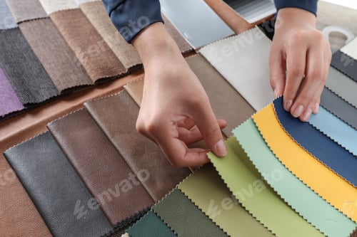 Preview: Young woman choosing among upholstery fabric samples, closeup. Interior design