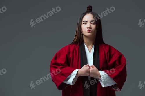 Preview: serious asian woman in traditional japanese kimono looking at camera isolated on grey