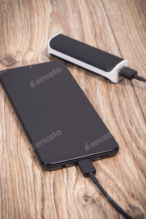 Preview: External powerbank using to charge empty battery of black smartphone
