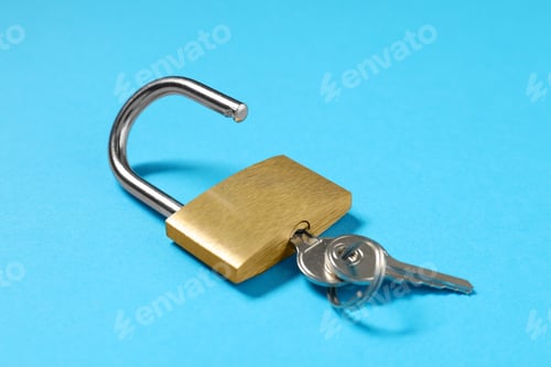 Preview: Steel padlock with keys on light blue background, closeup