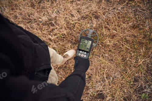 Preview: Information on the display. Man is with metal detector in the field