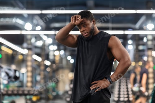 Preview: Exhausted black sportsman cleaning sweat from his forehead