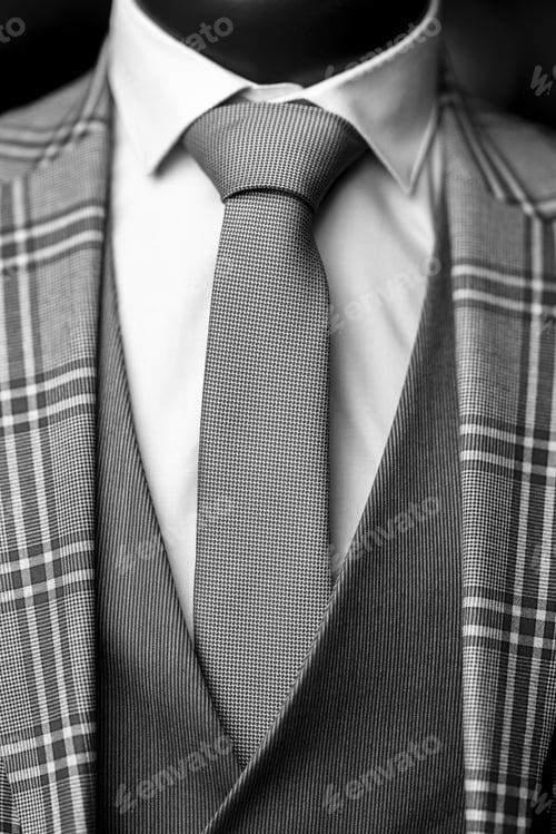 Preview: Vertical closeup shot of an elegant formal suit with a white shirt, gray tie, and patterned blazer