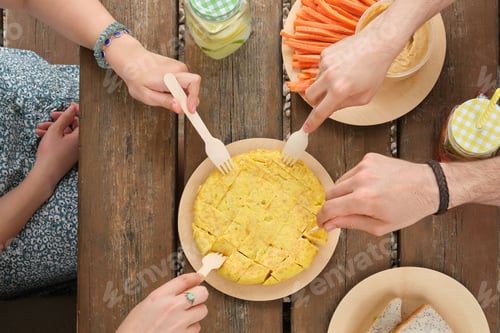 Preview: Group of unrecognizable happy friends taking a piece of spanish omelette with a fork in a park