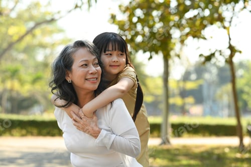 Preview: Image of smiling idle age grandmother giving piggyback ride to cute little granddaughter