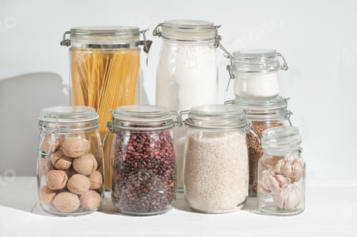 Preview: glass jars with grains and pasta, nuts and sugar on a kitchen table. sustainable home