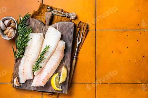 Preview: Raw cod fish fillets, codfish with rosemary on wooden board. Orange background. Top view. Copy space