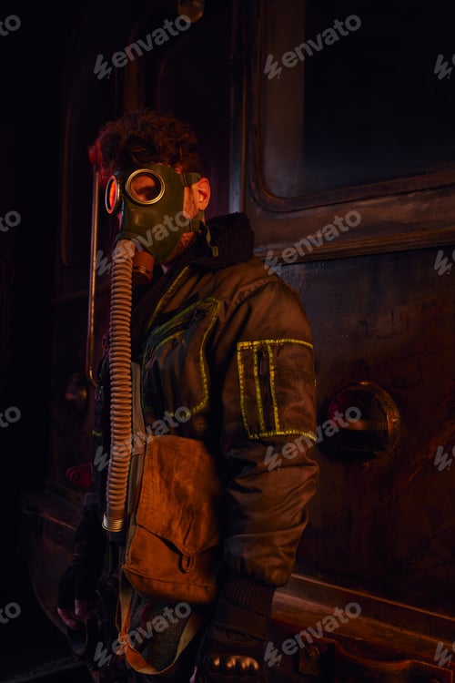 Preview: man in dirty jacket and gas mask near rusty subway carriage in abandoned underground tunnel