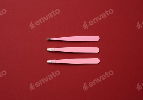 Preview: Various metal eyebrow tweezers on a red background