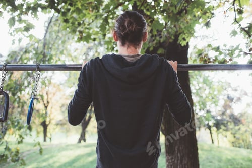Preview: Back view athletic man pulled up on sport rings training