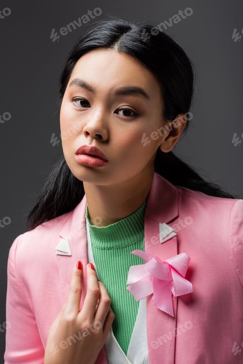 Preview: Portrait of asian woman in pink jacket looking at camera isolated on grey