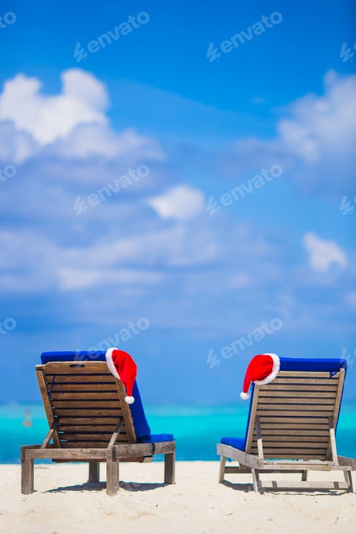Preview: Red santa hat and Christmas stocking on chair longue at tropical white beach
