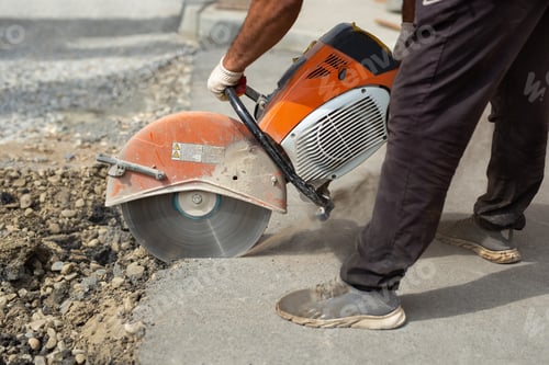 Preview: A road builder in uniform cuts off the old asphalt with a hand grinder according to the markings.