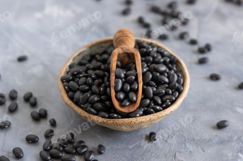 Preview: Ceramic bowl with dry black beans with a wooden scoop
