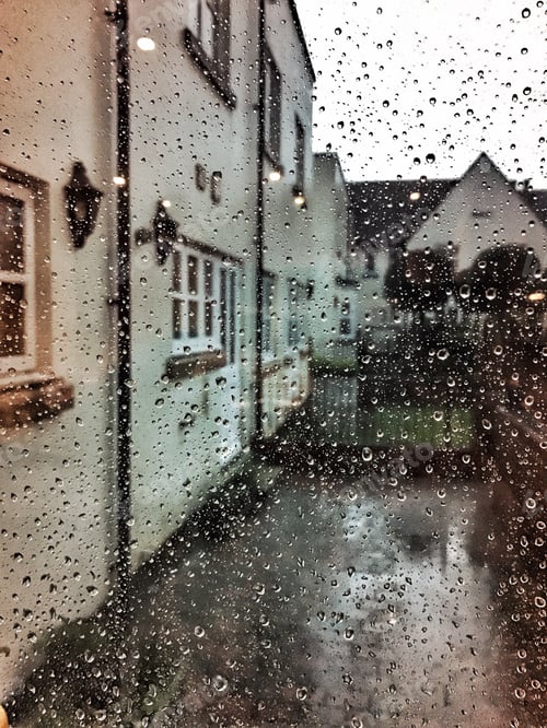Preview: Looking out of a window covered in raindrops to a residential area in the pouring rain