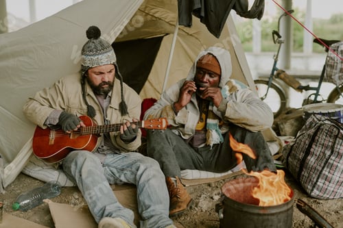 Preview: Homeless Caucasian Man and Black Man Playing Music Together Outdoors