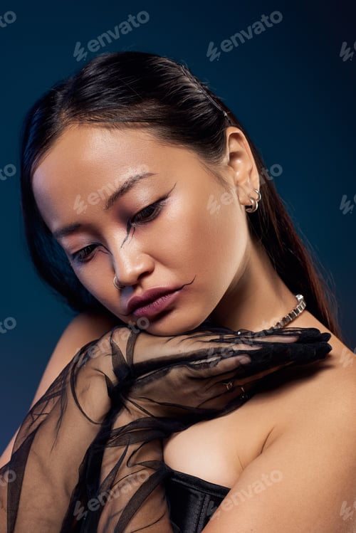Preview: Young woman showcases creative spooky makeup in dark corset against blue backdrop