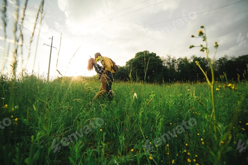 Preview: Loving hipster couple walking in the field, kissing and holding hands, hugging, lying in the grass
