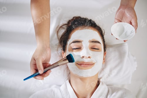Preview: Cosmetologist applying white clay mask