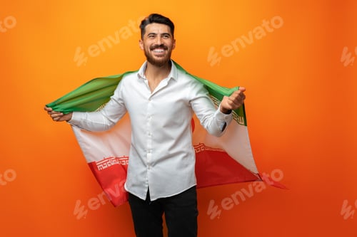 Preview: Portrait of a young casual man holding flag of Iran against orange background