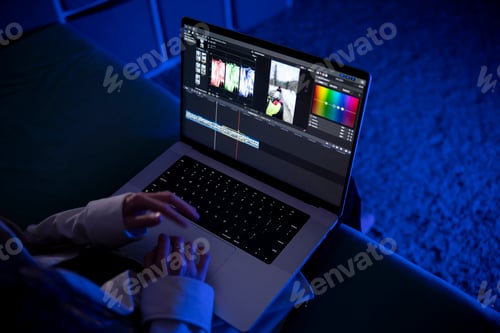Preview: Video Editor Working on Laptop With Editing Software in a Dimly Lit Room in the night