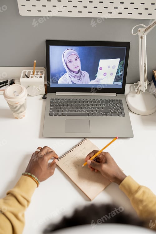 Preview: Hands of student making notes in front of laptop