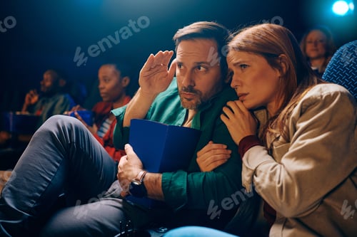 Preview: Shocked couple watching horror film at movie theater.