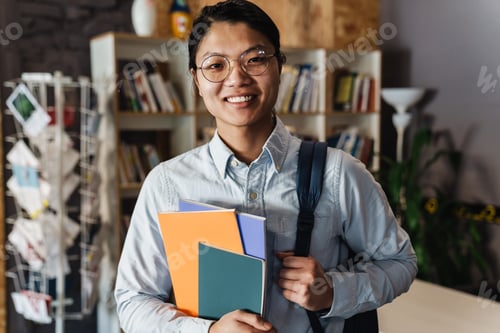 Preview: Image of happy asian man smiling and holding exercise books