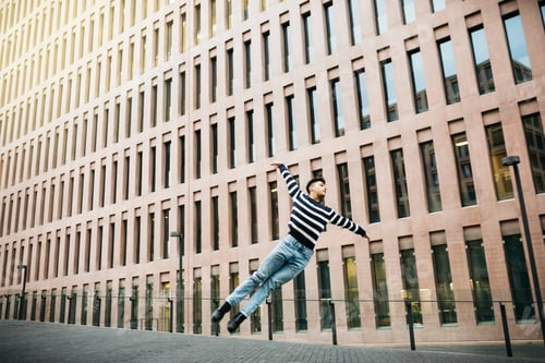 Preview: Young man joyfully leaping in urban setting
