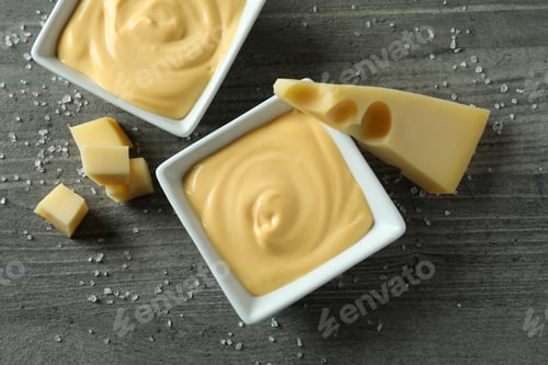 Preview: Bowls with cheese sauce, cheese and salt on gray textured table